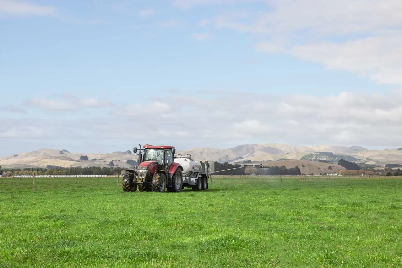 A Tow and Fert unit behind a tractor applying foliar fertiliser across pasture